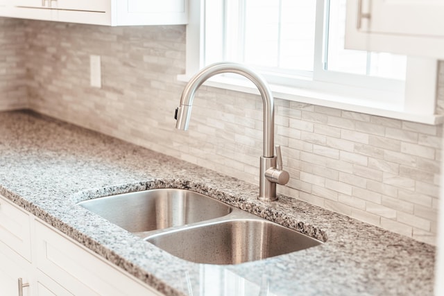 kitchen with white cabinets, sink, and tasteful backsplash