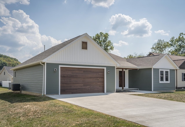 view of front of home with a front lawn, central AC unit, and a garage