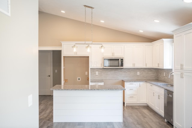 kitchen with stainless steel appliances, sink, pendant lighting, a kitchen island, and lofted ceiling