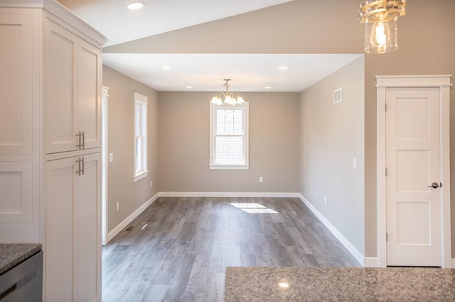 unfurnished dining area with a chandelier, lofted ceiling, and wood-type flooring