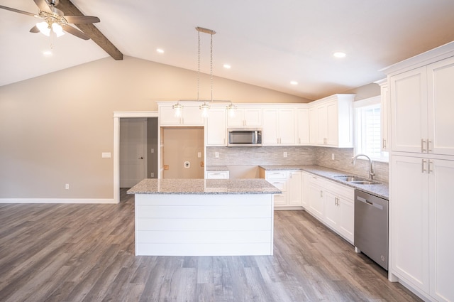 kitchen featuring sink, vaulted ceiling with beams, a kitchen island, white cabinetry, and stainless steel appliances