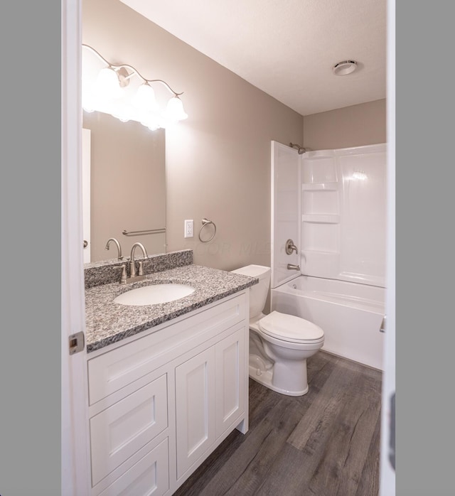 full bathroom featuring hardwood / wood-style floors, vanity, toilet, and washtub / shower combination