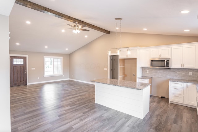 kitchen featuring hardwood / wood-style floors, lofted ceiling with beams, a kitchen island, and white cabinetry