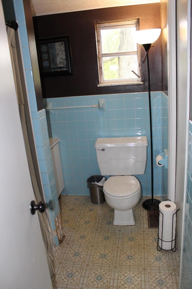 bathroom featuring tile walls and toilet