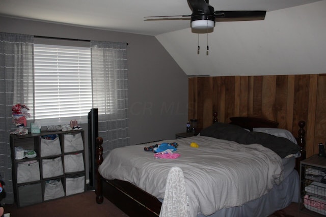 bedroom featuring ceiling fan, lofted ceiling, and wooden walls