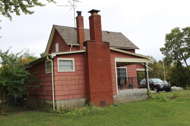 view of side of home featuring covered porch and a yard