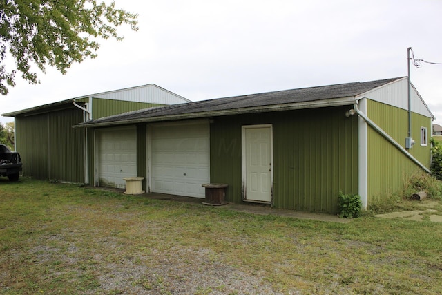 back of house with a lawn, a garage, and an outbuilding