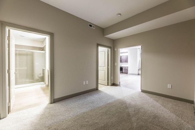 unfurnished bedroom featuring ensuite bath and light carpet