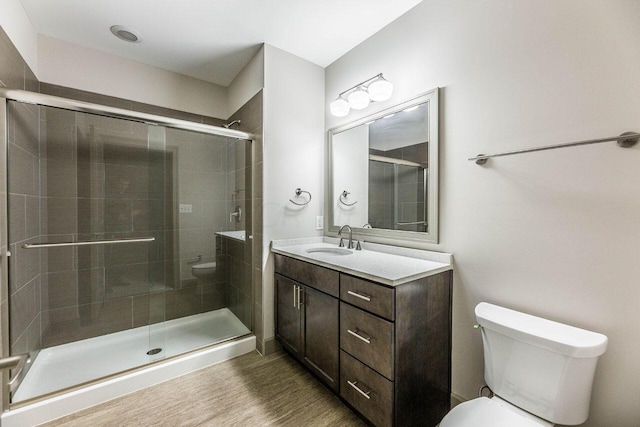 bathroom with hardwood / wood-style floors, vanity, a shower with shower door, and toilet