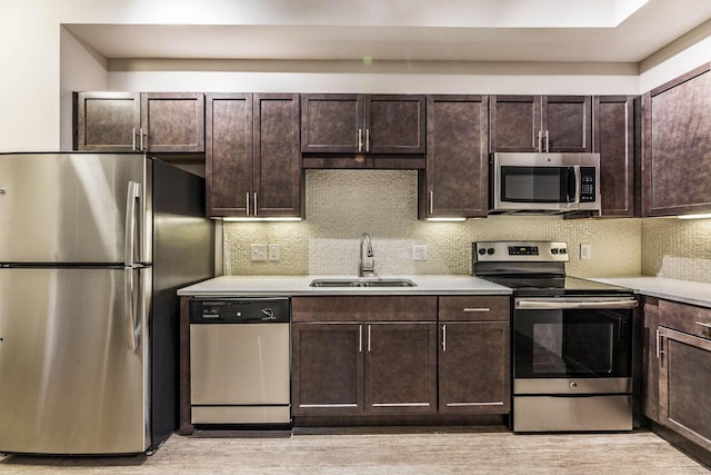 kitchen featuring dark brown cabinets, backsplash, stainless steel appliances, and sink