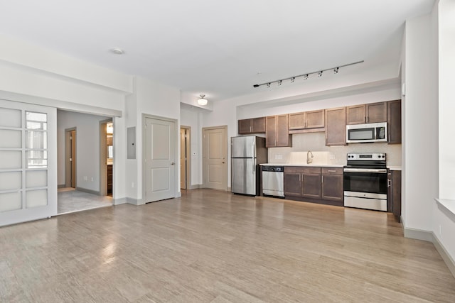 kitchen featuring light hardwood / wood-style flooring, rail lighting, stainless steel appliances, and sink