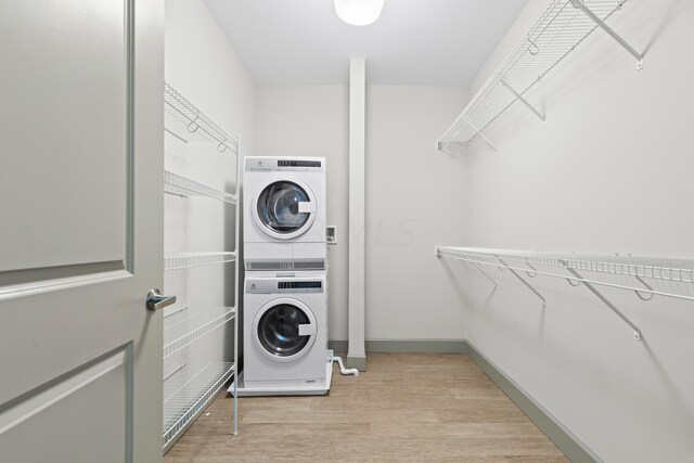 washroom with stacked washing maching and dryer and light hardwood / wood-style floors