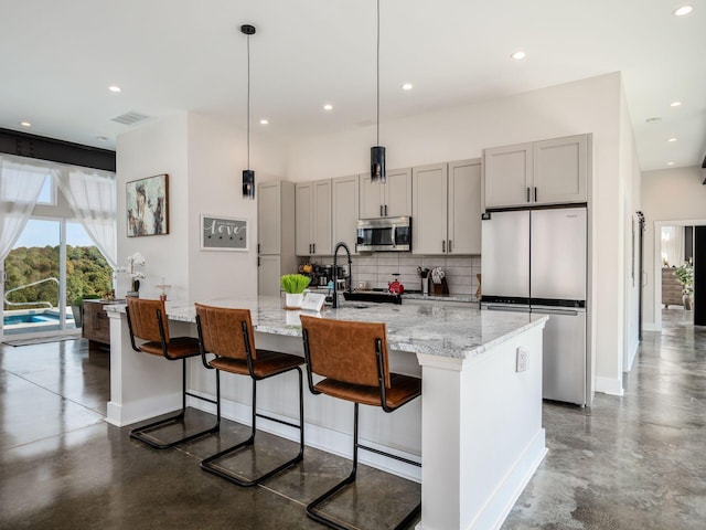 kitchen with appliances with stainless steel finishes, backsplash, a large island with sink, and gray cabinetry