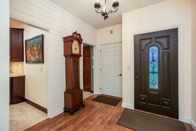 foyer entrance featuring wood walls, hardwood / wood-style floors, and a chandelier