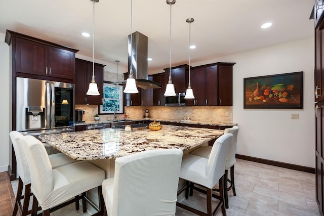 kitchen featuring a breakfast bar, a kitchen island, light stone countertops, and hanging light fixtures