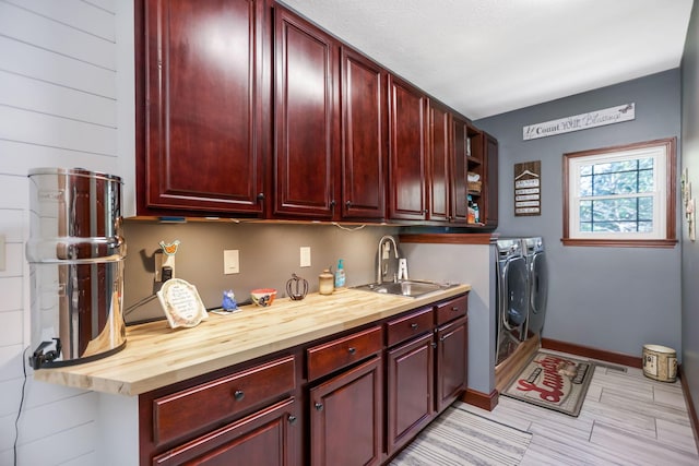 clothes washing area with cabinets, washing machine and dryer, and sink