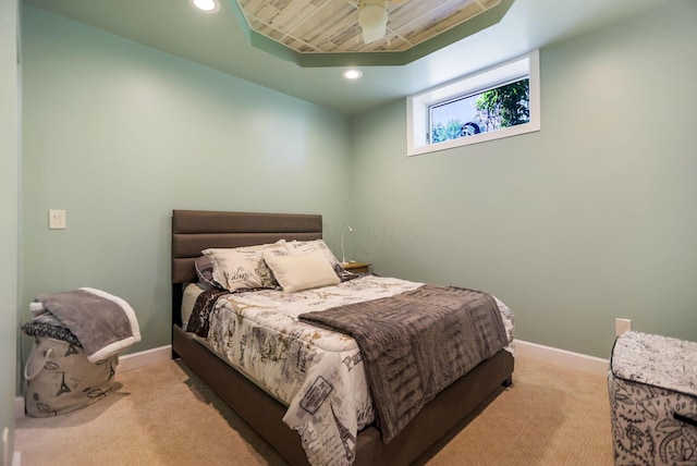 carpeted bedroom featuring ceiling fan and a raised ceiling