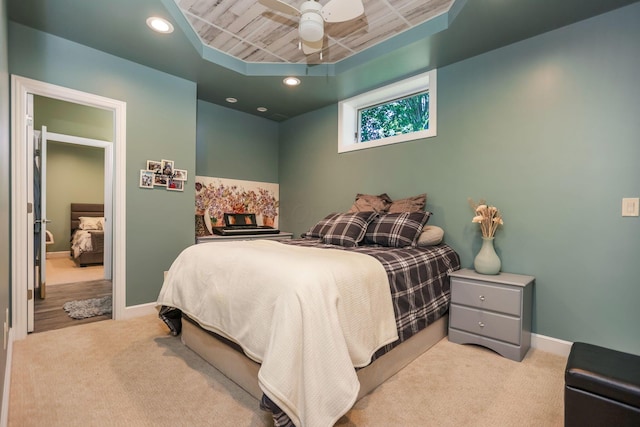 bedroom featuring a tray ceiling, ceiling fan, wood ceiling, and light carpet