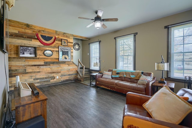 living room featuring ceiling fan, dark wood-type flooring, and wood walls