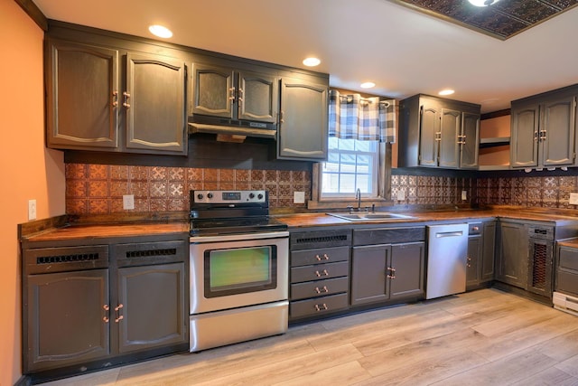 kitchen with light wood-type flooring, butcher block counters, sink, and appliances with stainless steel finishes