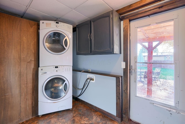 laundry room with stacked washer / dryer and cabinets