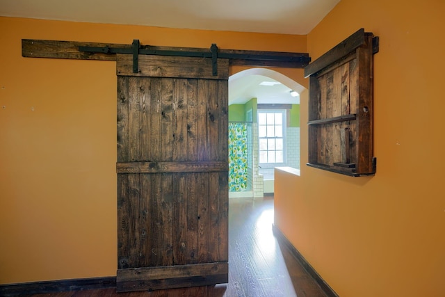 corridor with a barn door and dark wood-type flooring