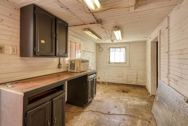 basement with a workshop area, wood ceiling, wood walls, and brick wall