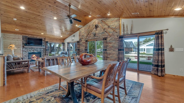 dining area featuring wooden ceiling, high vaulted ceiling, light hardwood / wood-style flooring, ceiling fan, and a fireplace