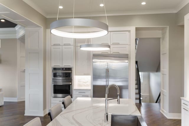 kitchen with dark wood finished floors, light stone countertops, ornamental molding, stainless steel appliances, and baseboards