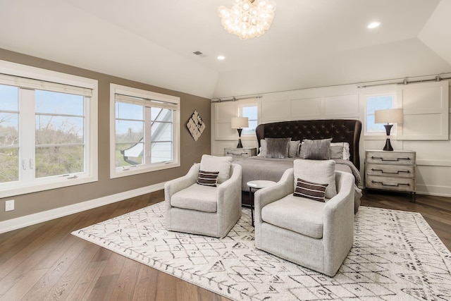 bedroom featuring an inviting chandelier, visible vents, wood finished floors, lofted ceiling, and baseboards