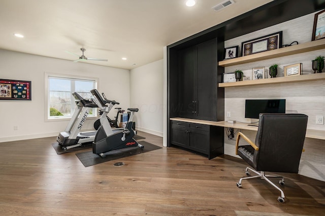 exercise room featuring visible vents, baseboards, a ceiling fan, and wood finished floors