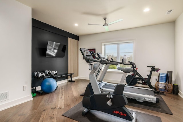 workout area featuring visible vents, baseboards, ceiling fan, and wood finished floors