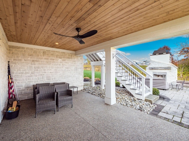 view of patio featuring ceiling fan, an outdoor fireplace, and stairway