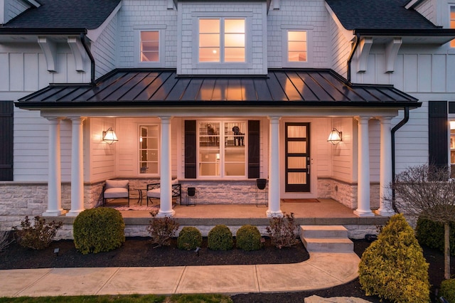 exterior space featuring metal roof, stone siding, covered porch, and a standing seam roof