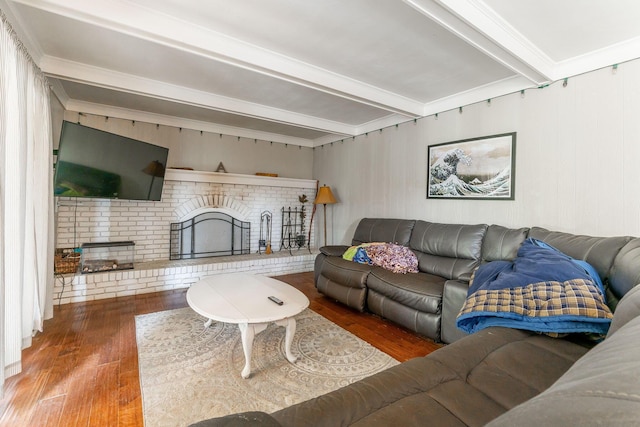 living room featuring beamed ceiling, wood-type flooring, and a brick fireplace