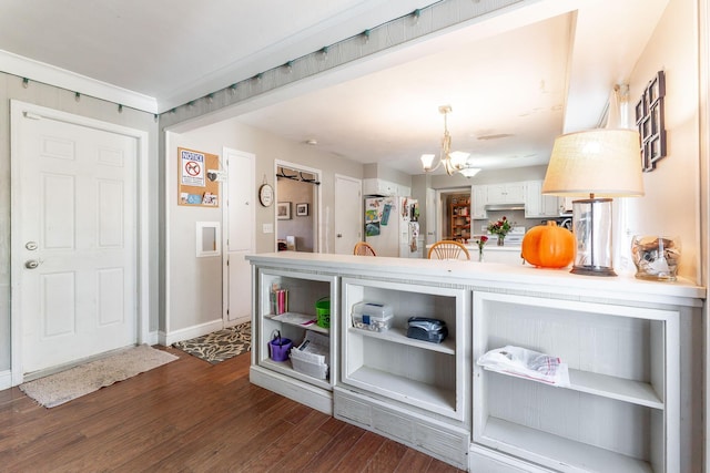 kitchen with dark wood-type flooring, an inviting chandelier, ornamental molding, white fridge with ice dispenser, and decorative light fixtures