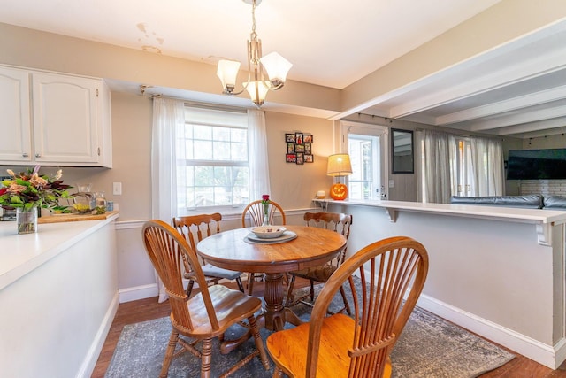 dining space featuring beamed ceiling, dark hardwood / wood-style floors, an inviting chandelier, and a healthy amount of sunlight