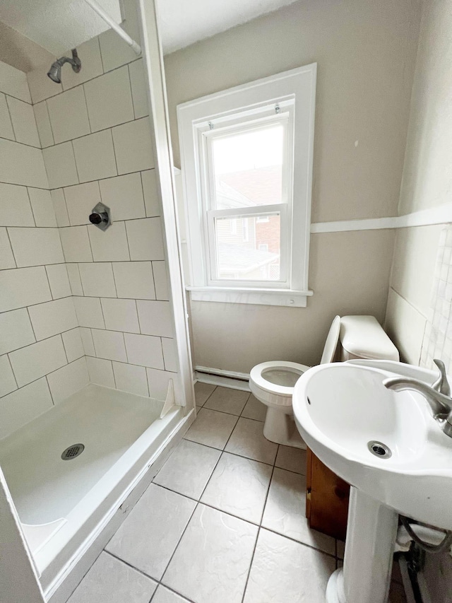 bathroom featuring toilet, tile patterned flooring, and tiled shower