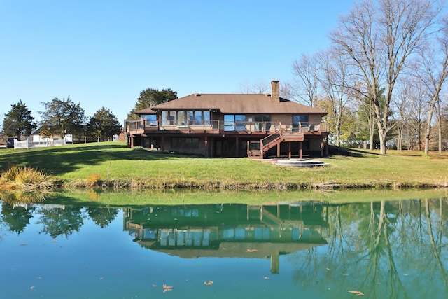 back of property with a lawn and a deck with water view