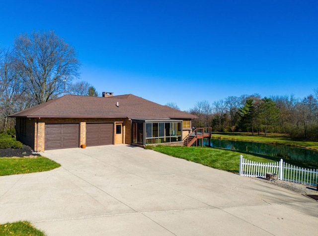 ranch-style house featuring a garage, a water view, and a front lawn