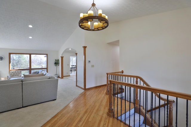 corridor featuring a notable chandelier, light hardwood / wood-style flooring, and vaulted ceiling