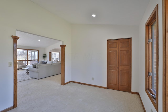 carpeted empty room with lofted ceiling and ornate columns