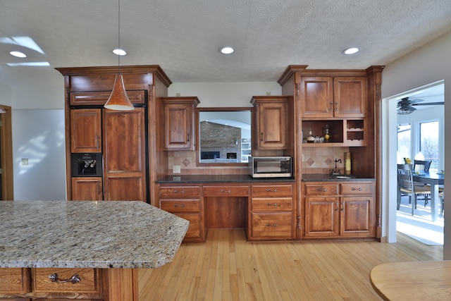 kitchen featuring light stone countertops, pendant lighting, tasteful backsplash, and light hardwood / wood-style floors