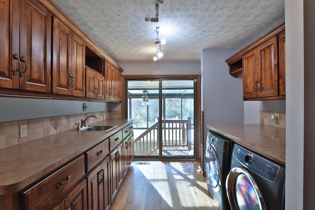 kitchen with tasteful backsplash, a textured ceiling, sink, washer and dryer, and light hardwood / wood-style floors