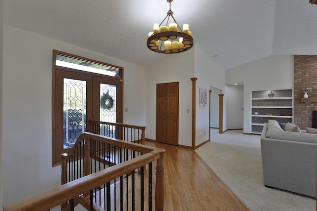 entrance foyer featuring a chandelier, light wood-type flooring, and vaulted ceiling