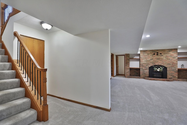 stairway with a fireplace and carpet floors