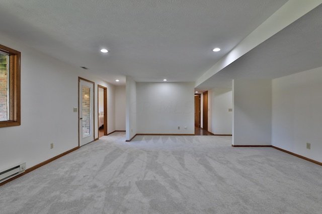 spare room featuring a textured ceiling, light colored carpet, and baseboard heating