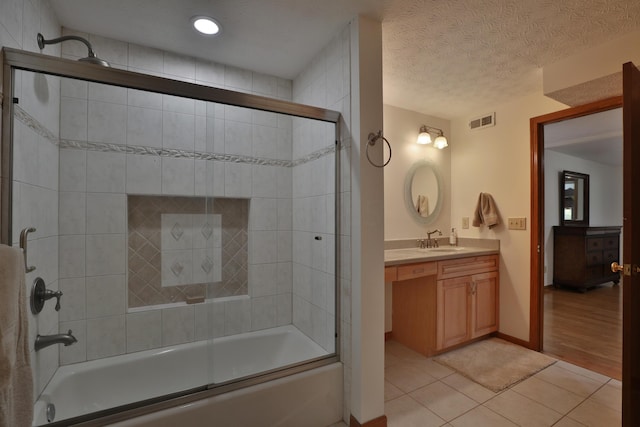 bathroom featuring hardwood / wood-style flooring, vanity, bath / shower combo with glass door, and a textured ceiling