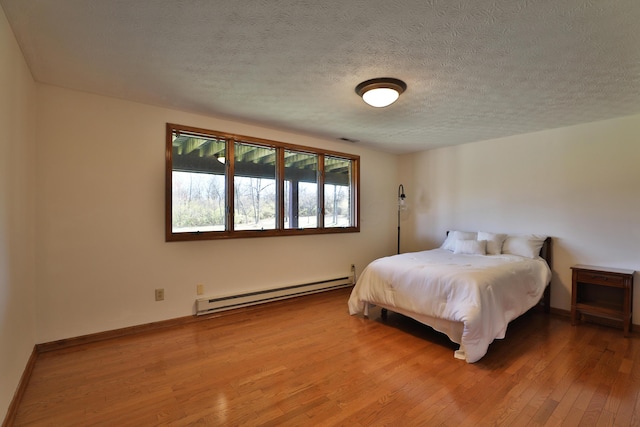 bedroom with wood-type flooring, a textured ceiling, and a baseboard radiator