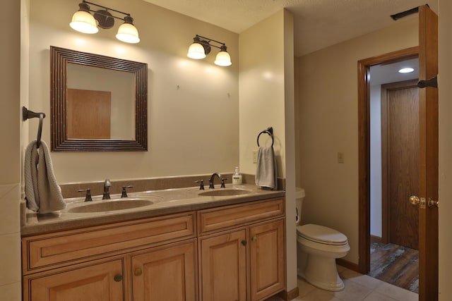 bathroom featuring vanity, a textured ceiling, hardwood / wood-style flooring, and toilet